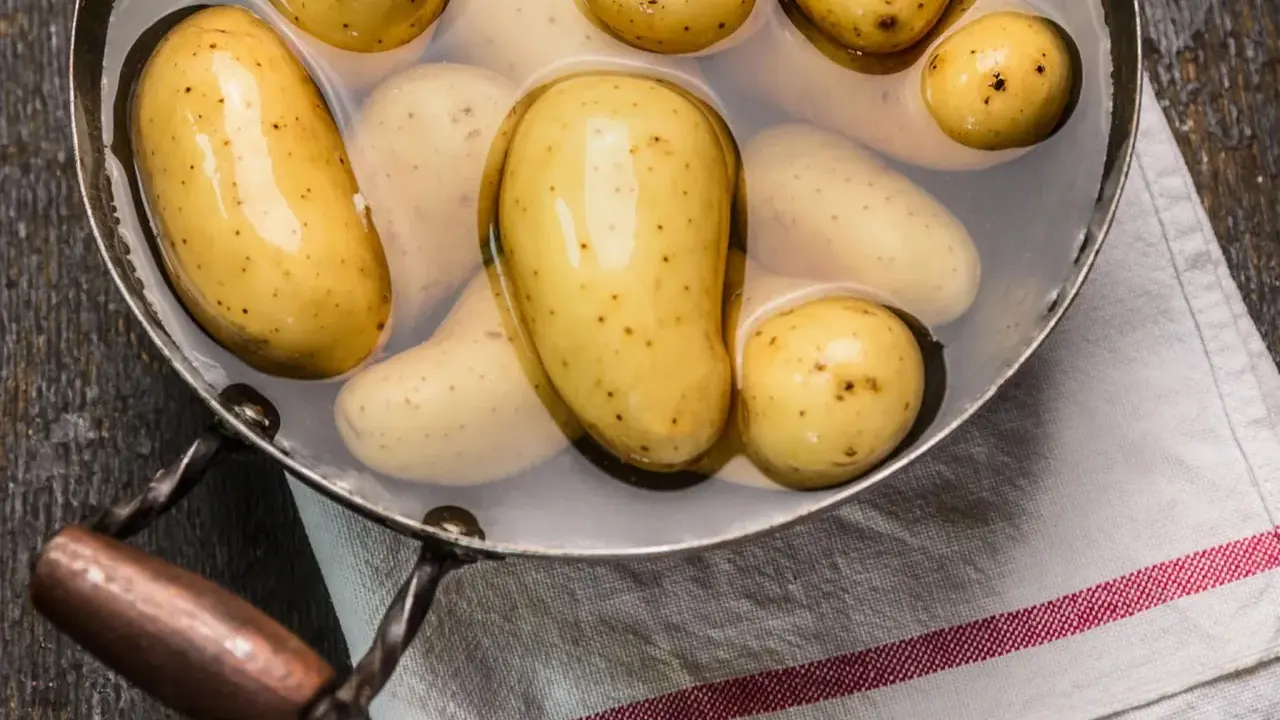 Kleine, gelbe Kartoffeln liegen in einem Topf mit Wasser. Sie warten darauf, gekocht zu werden, um später als Beilage zu dienen.