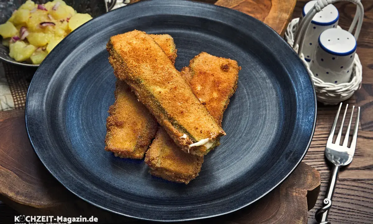 Knusprig panierte Zucchini-Sticks, ein köstliches Gericht, das perfekt zu vielen zucchini rezepte passt. Daneben Kartoffelsalat.
