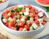Erfrischender melonen feta salat mit Gurken und Minze in einer weißen Schüssel, bereit zum Servieren.