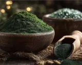 Grünes Pulver in Holzschalen und Löffel. Das ist Spirulina, ein nährstoffreiches Superfood.