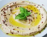 Cremiger Hummus, garniert mit Öl, Kräutern und Samen. Tahin ist die geheime Zutat für diese köstliche Dip-Kreation.
