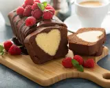 Schokoladen-Kastenkuchen mit einem hellen Herz im Inneren, garniert mit frischen Himbeeren und Schokoladensauce.