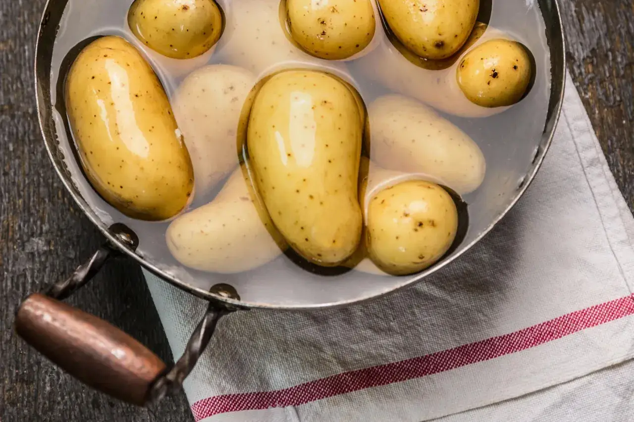 Kleine, gelbe Kartoffeln liegen in einem Topf mit Wasser. Sie warten darauf, gekocht zu werden, um später als Beilage zu dienen.