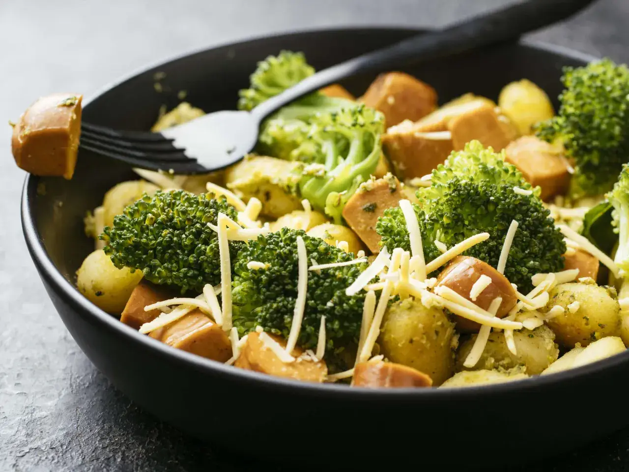 Ein schnelles Gericht mit Kartoffeln, Brokkoli und Würstchen, bestreut mit Käse. Perfekt für Rezepte mit wenig Zutaten.
