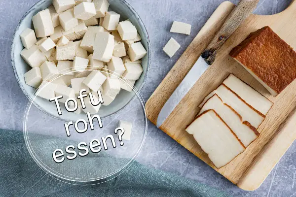 Würfel und Scheiben von Tofu liegen neben einem Messer auf einem Holzbrett. Die Frage "Kann man Tofu roh essen?" wird gestellt.