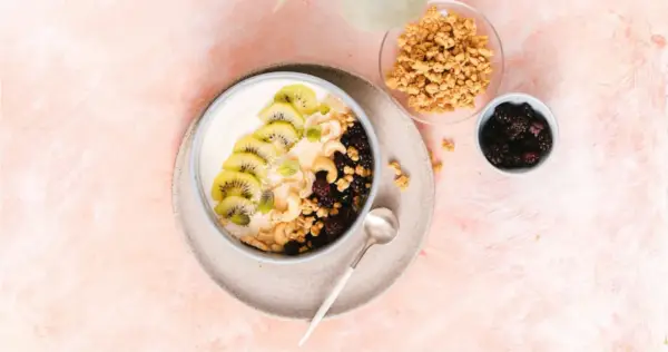 Gesunder Joghurt-Bowl mit Kiwi, Beeren, Nüssen und Granola – perfekt für proteinreiche Mahlzeiten.