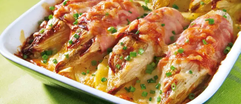 Gebackener Chicorée in Schinken gewickelt, überbacken mit Käse und Kartoffeln. Ein köstliches Gericht für alle, die Rezepte mit Schinken lieben.