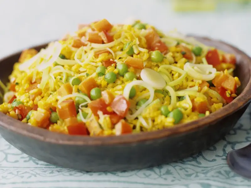 Bunter Reis mit Erbsen, Karotten und Lauchringen, inspiriert von Safran-Rezepten.
